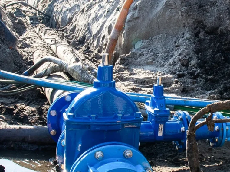 Blauwe afsluiter in een waterleiding in een open sleuf, tussen andere kabels en leidingen