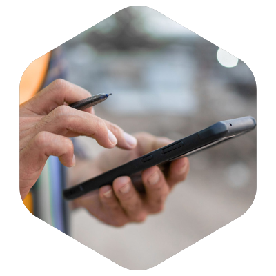 Handen met een pen en een smartphone, buiten gefotografeerd in een zeshoekige uitsnede