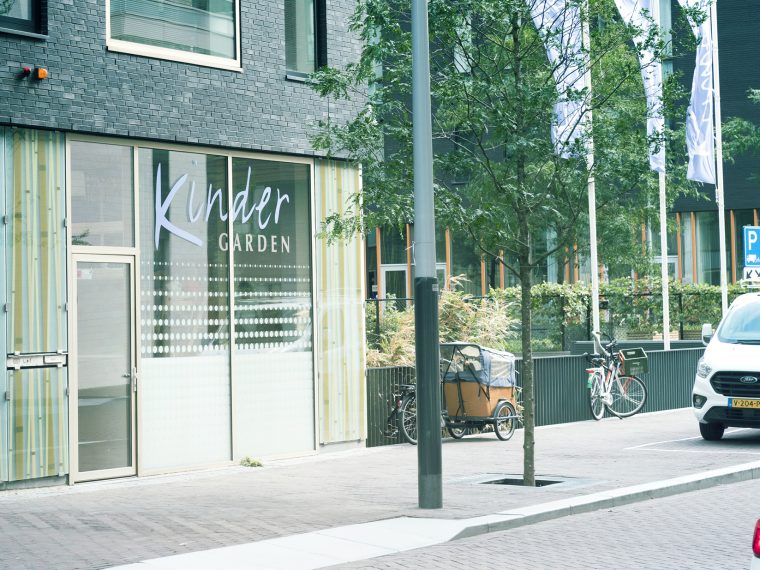 Gevel van een Kindergarden-vestiging met grote ramen, met fietsen en een bakfiets op de stoep