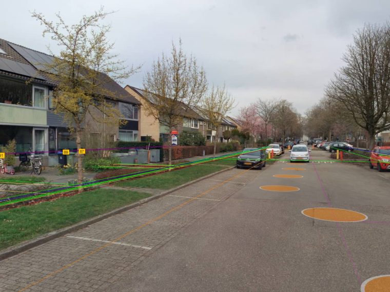 Panoramafoto van een woonstraat met gekleurde lijnen van kabels en leidingen en oranje cirkels op de rijbaan